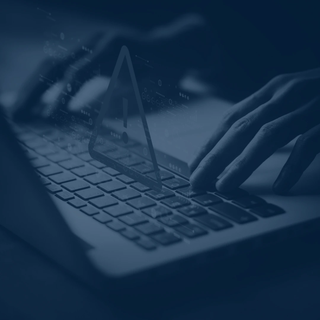 Hands typing on a laptop keyboard with a digital warning symbol, emphasizing security updates for electrotechnology training.